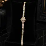 Gold plated zircon tennis bracelet with starburst flower center on black velvet display