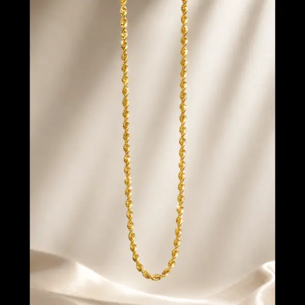 Classic gold twisted rope chain necklace suspended over elegant silk background