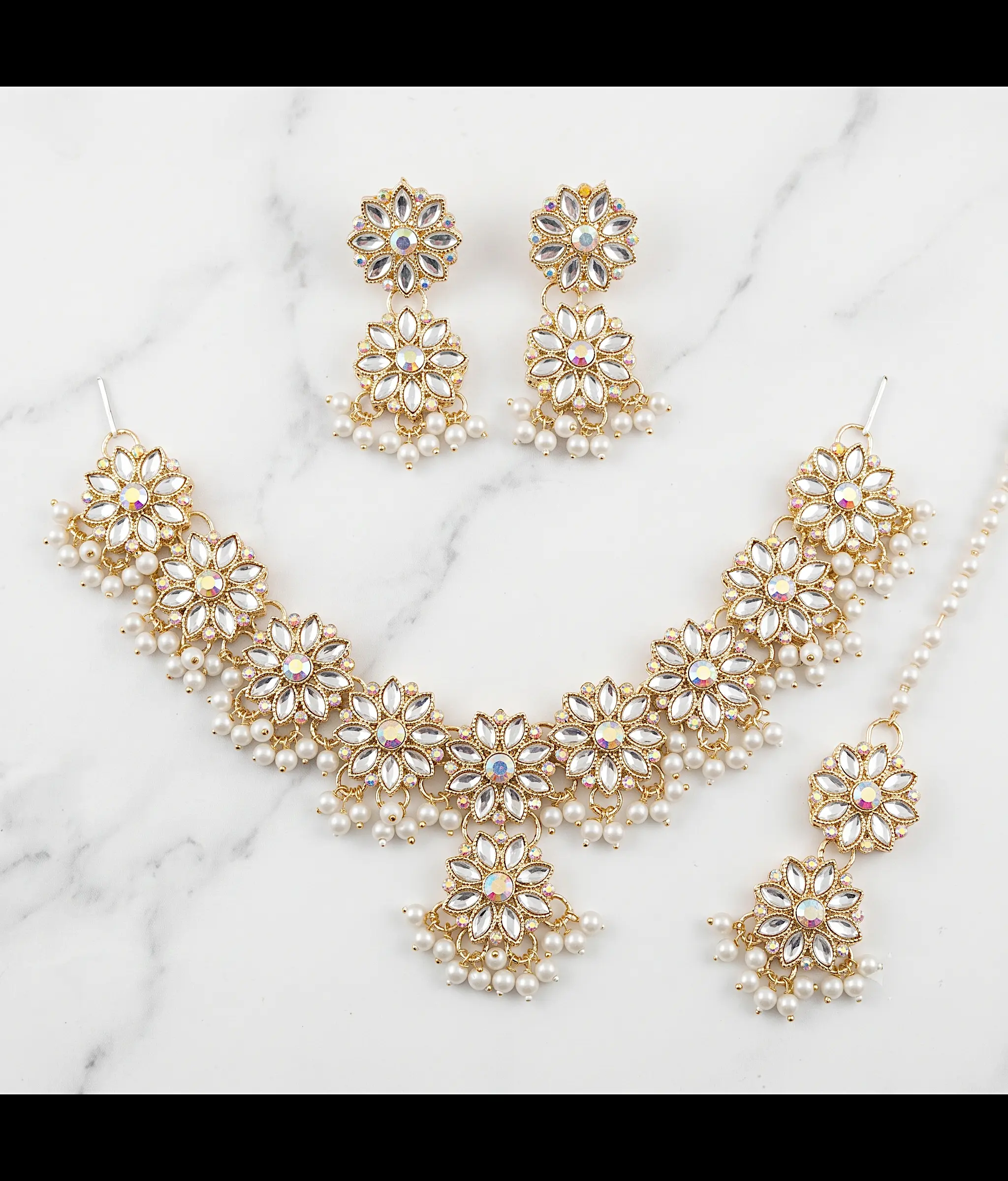 Gold floral Kundan jewelry set with necklace earrings and maang tikka featuring pearl drops