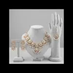 Gold floral Kundan jewelry set with necklace earrings and maang tikka featuring pearl drops