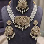 Bridal Kundan jewelry set featuring a multi-strand pearl choker necklace, matching circular drop earrings, and maang tikka