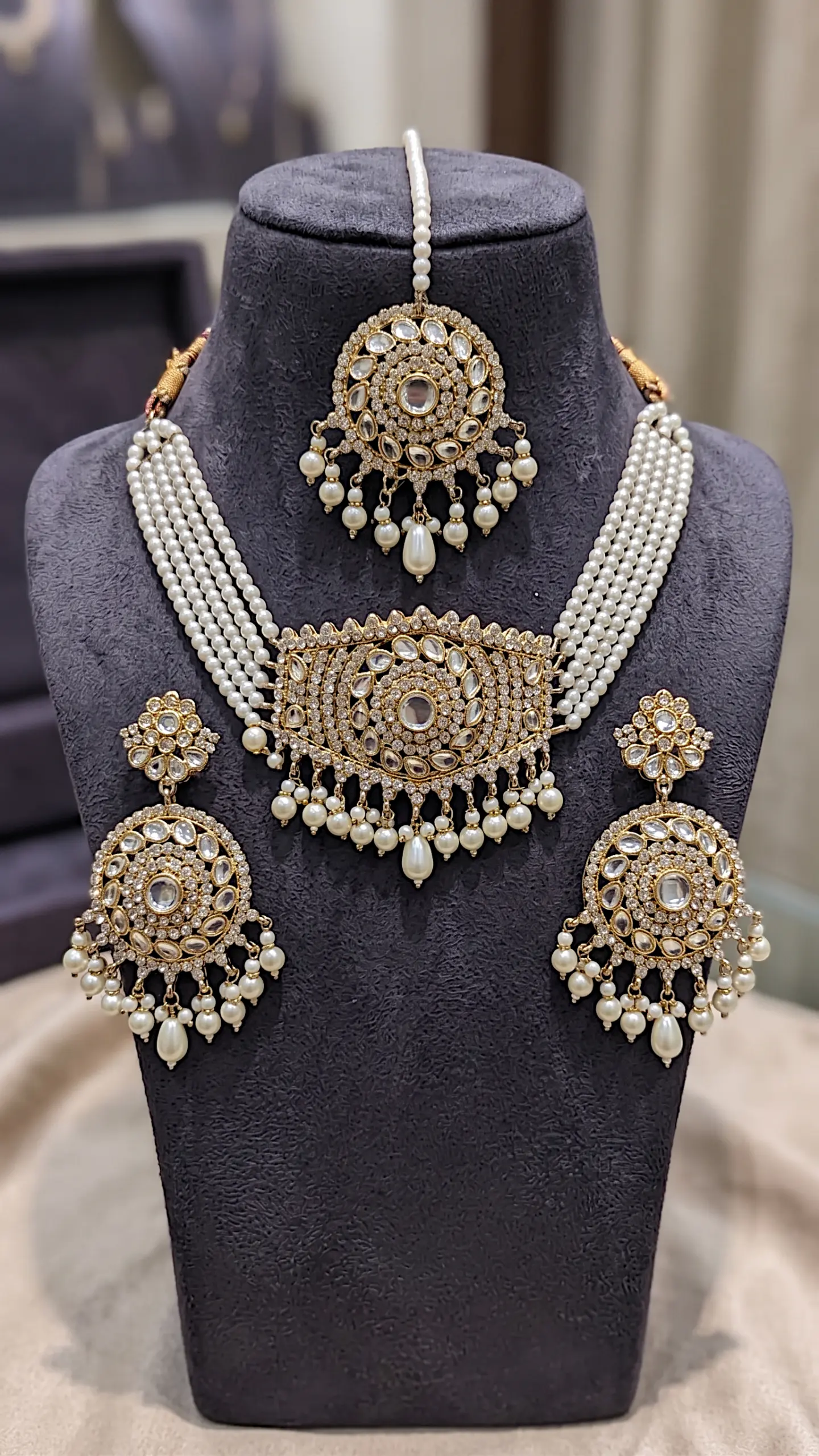 Bridal Kundan jewelry set featuring a multi-strand pearl choker necklace, matching circular drop earrings, and maang tikka